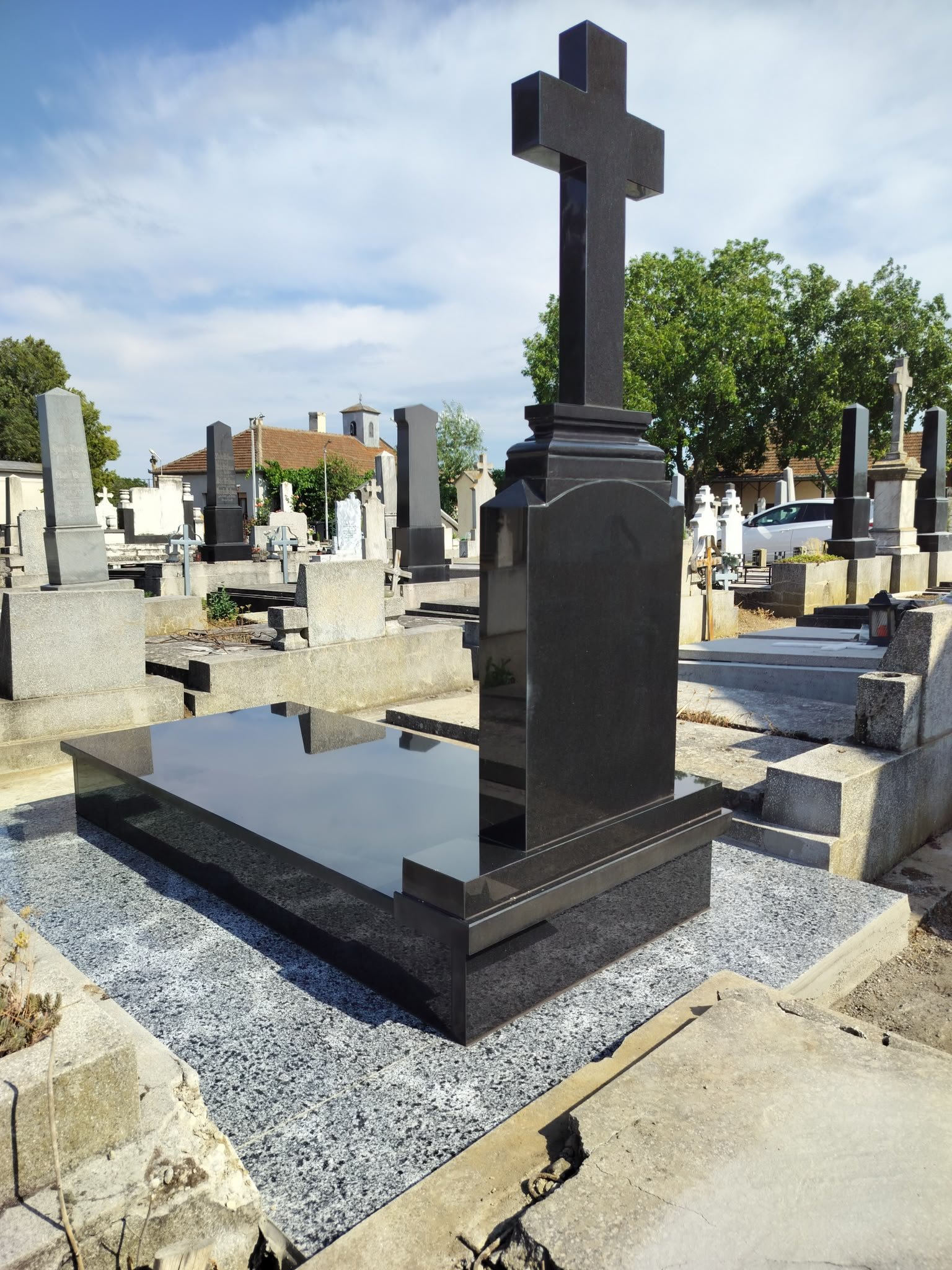 Monument funerar din granit negru cu cruce înaltă și capac lustruit